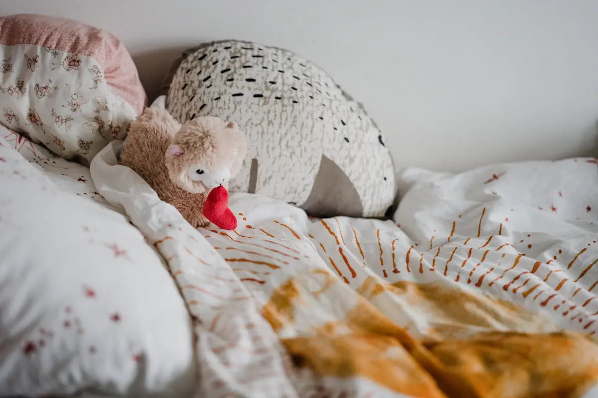 white and brown bear plush toy on white and orange floral textile